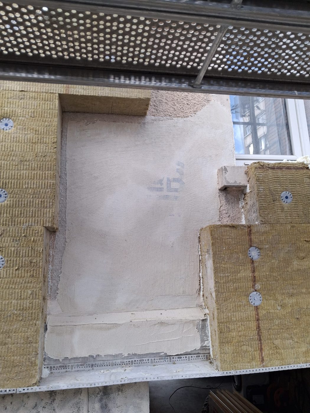 Reprise de planéité et sous-enduit armé d’une trame en fibre de verre sur la zone couturée, avant pose de l’isolation extérieure