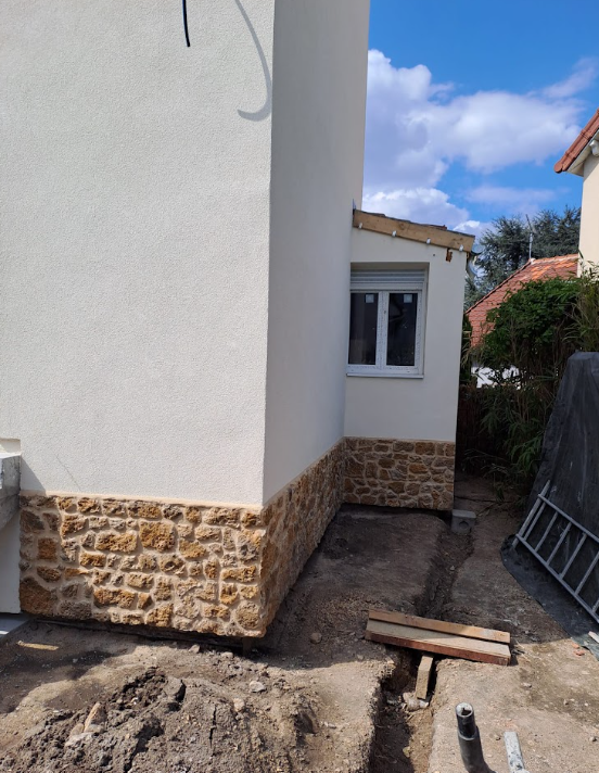 Maison isolée par l’extérieur avec enduit blanc cassé et soubassement en pierre de parement, chantier Rénoco