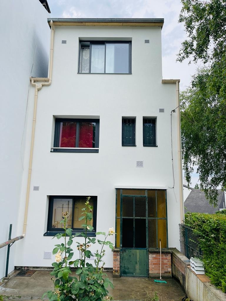 Façade d'entrée d'une maison à Bry-sur-Marne après isolation par l'extérieur, enduit taloché blanc et tableaux de fenêtres en retrait