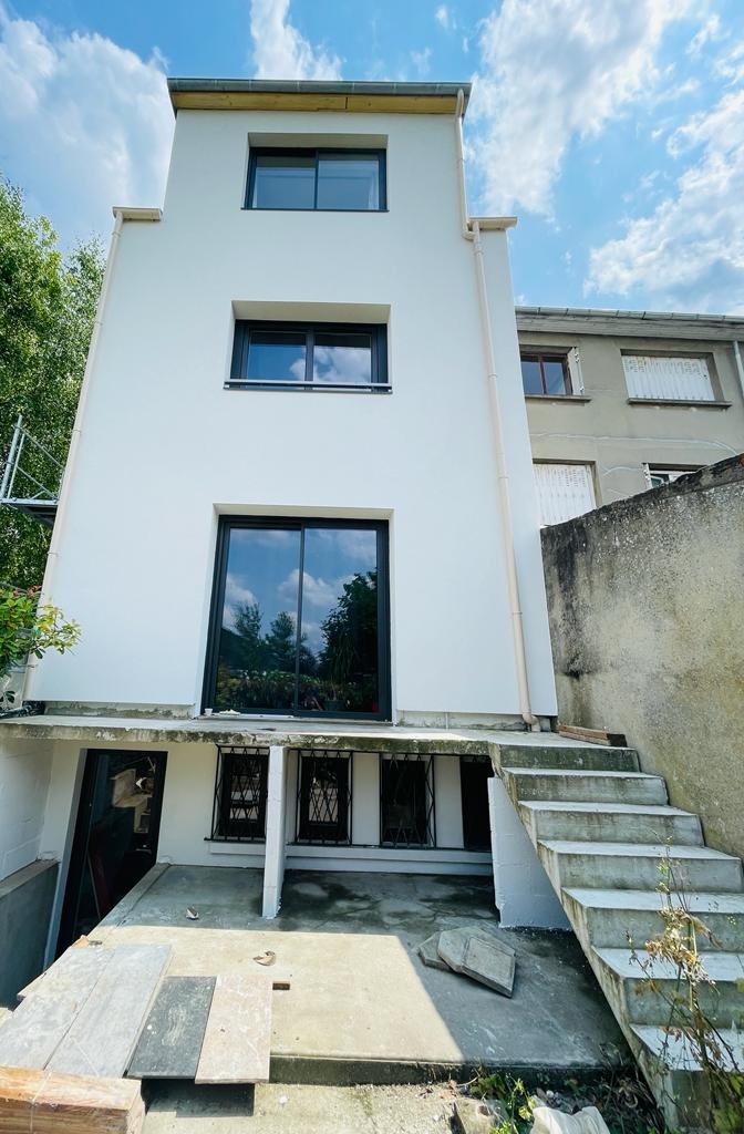 Façade côté jardin d'une maison à Bry-sur-Marne après isolation par l'extérieur : enduit taloché blanc StoLit K 1,5 sur la maison et l'extension