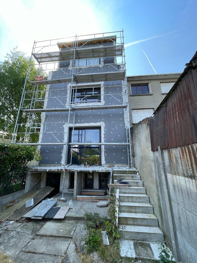 Façade côté jardin d'une maison à Bry-sur-Marne pendant l'isolation par l'extérieur : panneaux de PSE 120 mm posés sur la maison et l'extension