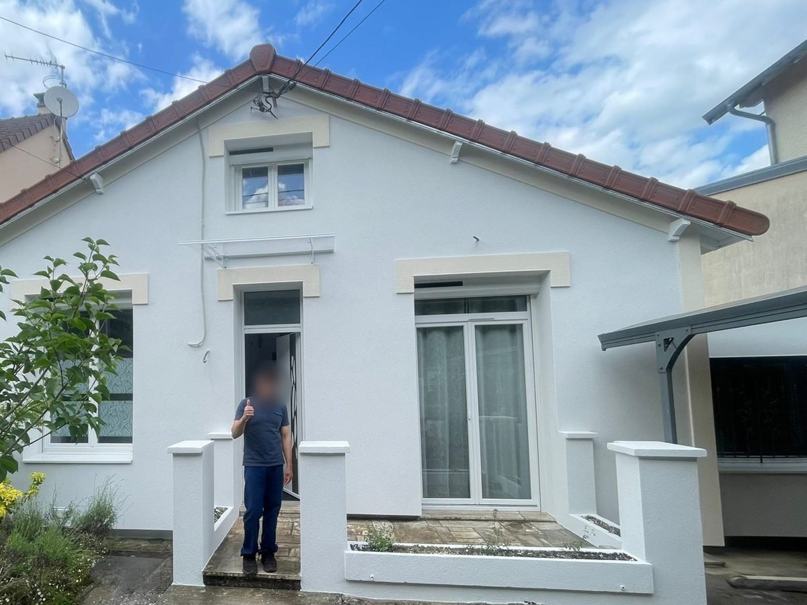 Façade d'entrée d'une maison à Champs-sur-Marne après isolation par l'extérieur, linteaux crème sur enduit blanc