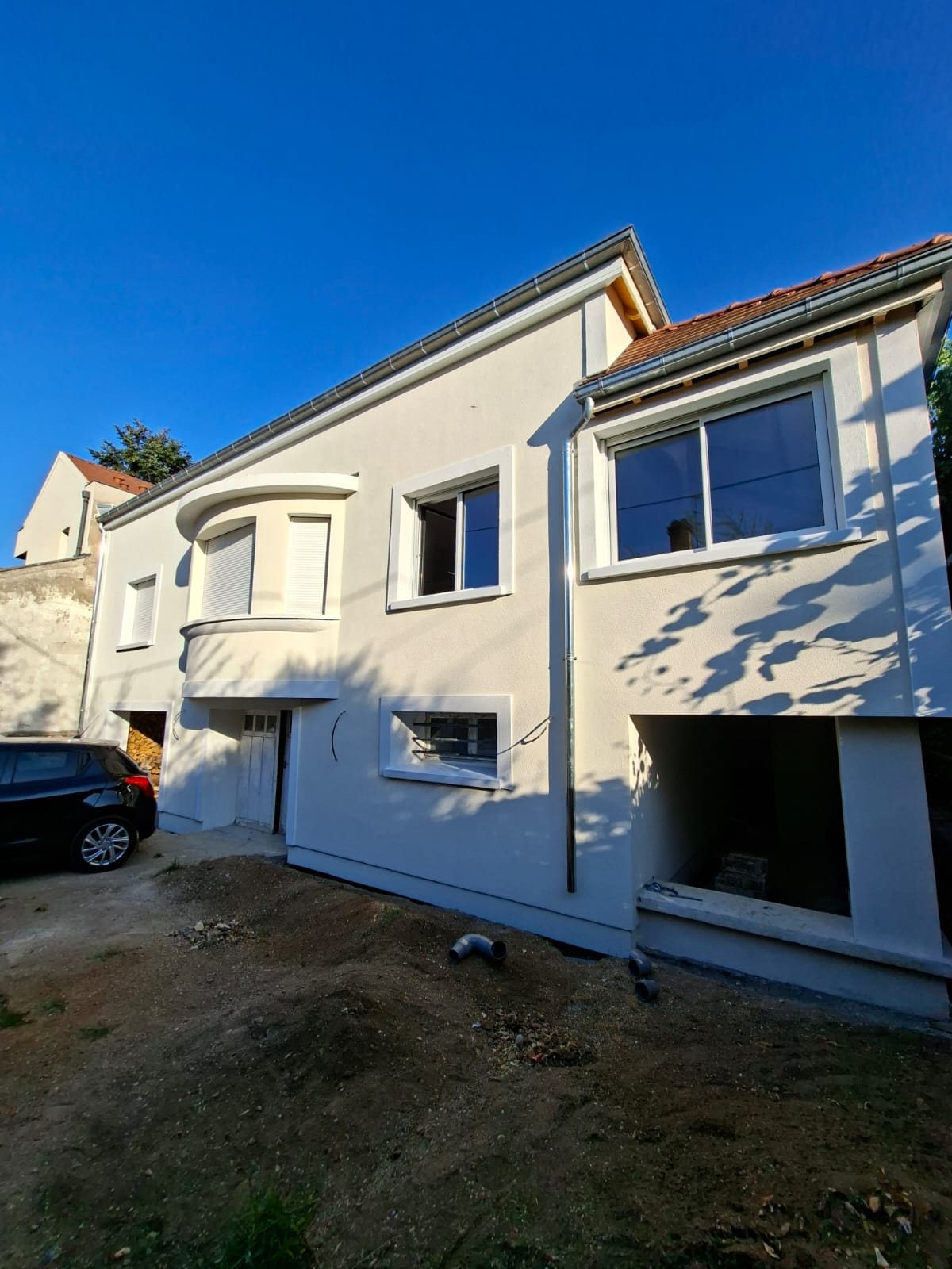 Maison à Créteil après isolation par l'extérieur : façade au même nu du soubassement à l'étage, bow-window arrondi et encadrements de fenêtres repris