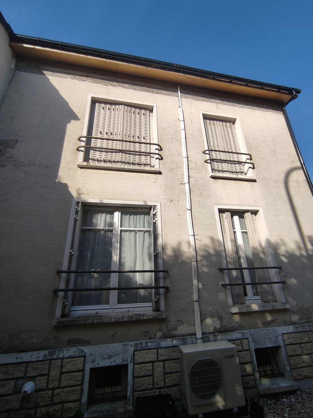Façade d'une maison au Perreux-sur-Marne avant isolation par l'extérieur : enduit encrassé et écaillé, encadrements de fenêtres et persiennes