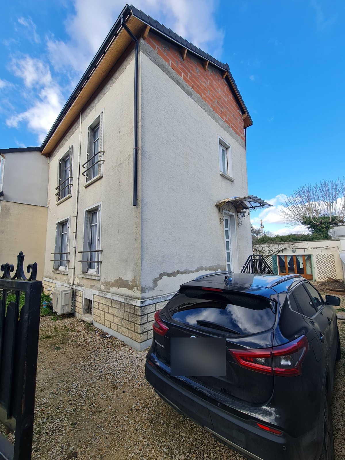 Pignon et façade d'entrée d'une maison au Perreux-sur-Marne avant isolation par l'extérieur : enduit qui se décolle en partie basse, surélévation en brique