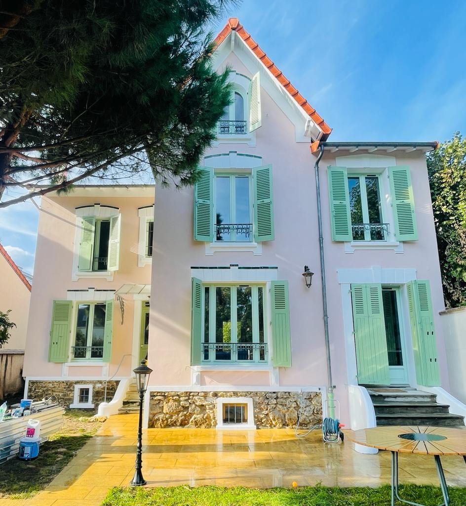 Maison de style provençal à Nogent-sur-Marne après ravalement : enduit rose, tableaux repris en blanc, volets battants repeints en vert et soubassement en meulière rejointoyé