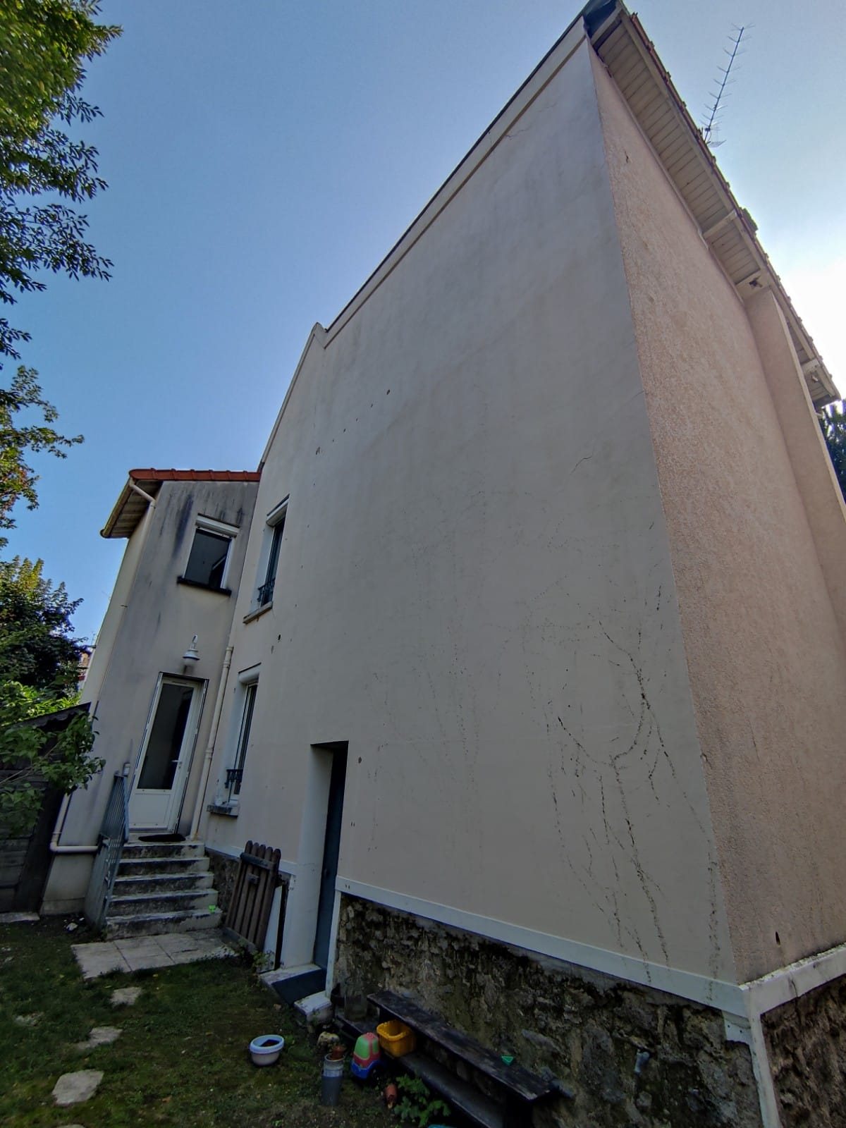 Façade arrière et pignon d'une maison à Nogent-sur-Marne avant isolation par l'extérieur : enduit fissuré au-dessus du soubassement en meulière
