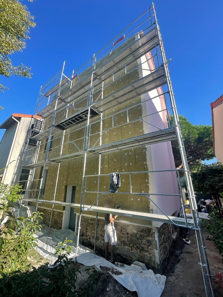 Pose des panneaux de laine de roche Ecorock Duo 140 mm sur la façade arrière d'une maison à Nogent-sur-Marne, au-dessus du soubassement en meulière