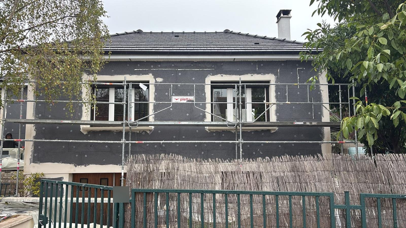 Pose de panneaux de PSE gris chevillés sur la façade d'un pavillon à Pontault-Combault, tableaux de fenêtres enduits