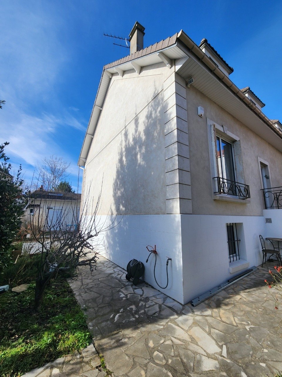 Pignon de la maison à Villiers-sur-Marne avant ITE : enduit taché, chaîne d'angle en relief et soubassement blanc