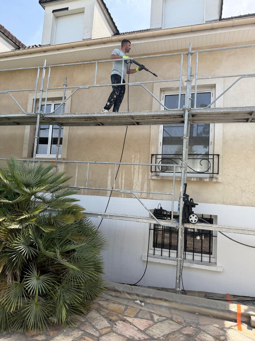Compagnon Rénoco nettoyant la façade de la maison à Villiers-sur-Marne au nettoyeur haute pression avant l'isolation
